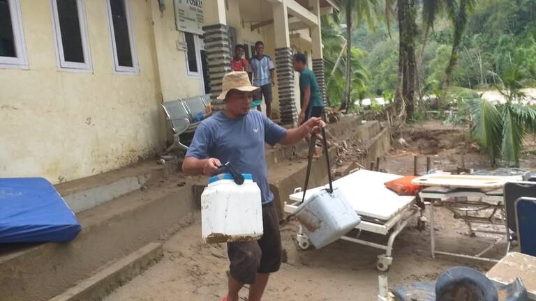 Masyarakat membersihkan sisa-sisa banjir di salah satu fasilitas kesehatan di Kecamatan Kapur IX.