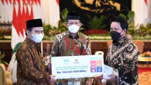 Direktur Utama PT Bank Syariah Indonesia Tbk (BSI) Hery Gunardi (kanan) menyerahkan zakat perusahaan dan zakat non perusahaan melalui BAZNAS sebesar Rp 122,5 Miliar. Disaksikan oleh Ketua BAZNAS RI Noor Ahmad (tengah) di Istana Negara Republik Indonesia. Jakarta (12/4/2022).