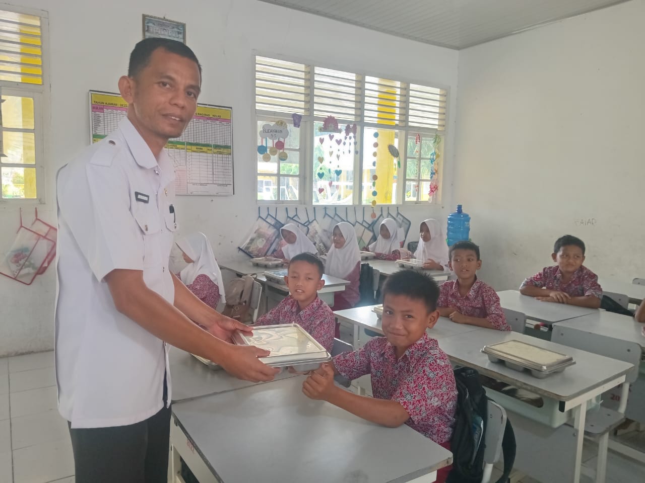 Kepala UPT SDN 04 Bariang Rao-rao,Kecamatan Sungai Pagu Kabupaten Solok Selatan Asbandi, S.Pd, M.Pd saat ikut mendistribusikan MBG kepada siswa.