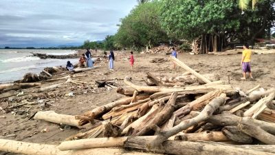 Warga menikmati berwisata di Pantai Parkit Padang yang dipenuhi tumpukan sampah kayu