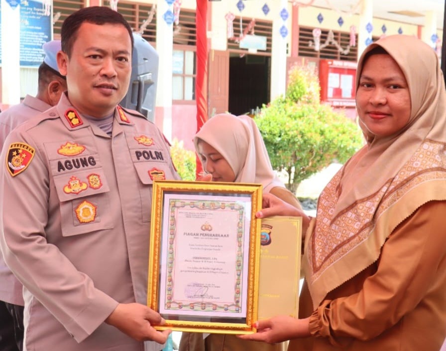 Kapolres Pasaman Barat AKBP. Agung Tribawanto menyerahkan penghargaan kepada guru berprestasi dan penanaman pohon di SDN 16 Pasaman, Selasa (05/05/2026).