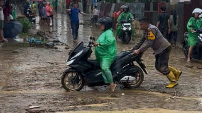 Bhabimkamtibmas Surau Gadang Aipda Windrizal saat membantu mendorong motor warga yang mogok di jalan.