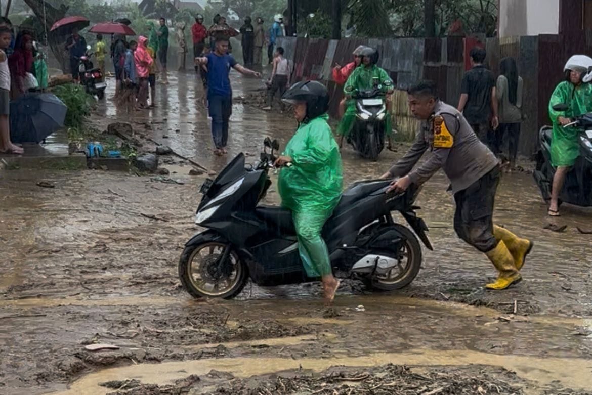 Bhabimkamtibmas Surau Gadang Aipda Windrizal saat membantu mendorong motor warga yang mogok di jalan.