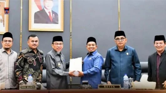 Ketua DPRD Kota Padang Muharlion saat menyerahkan persetujuan Ranperda Adat kepada Wakil Wali Kota Padang, Maigus Nasir, Sabtu (06/06/2026).
