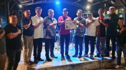 Ketua PWI Sumbar Widya Navies menyerahkan penghargaan kepada Kapolres Limapuluh Kota Syaiful Wachid di kawasan wisata Palano Hill, Jumat (17/07/2026) malam.