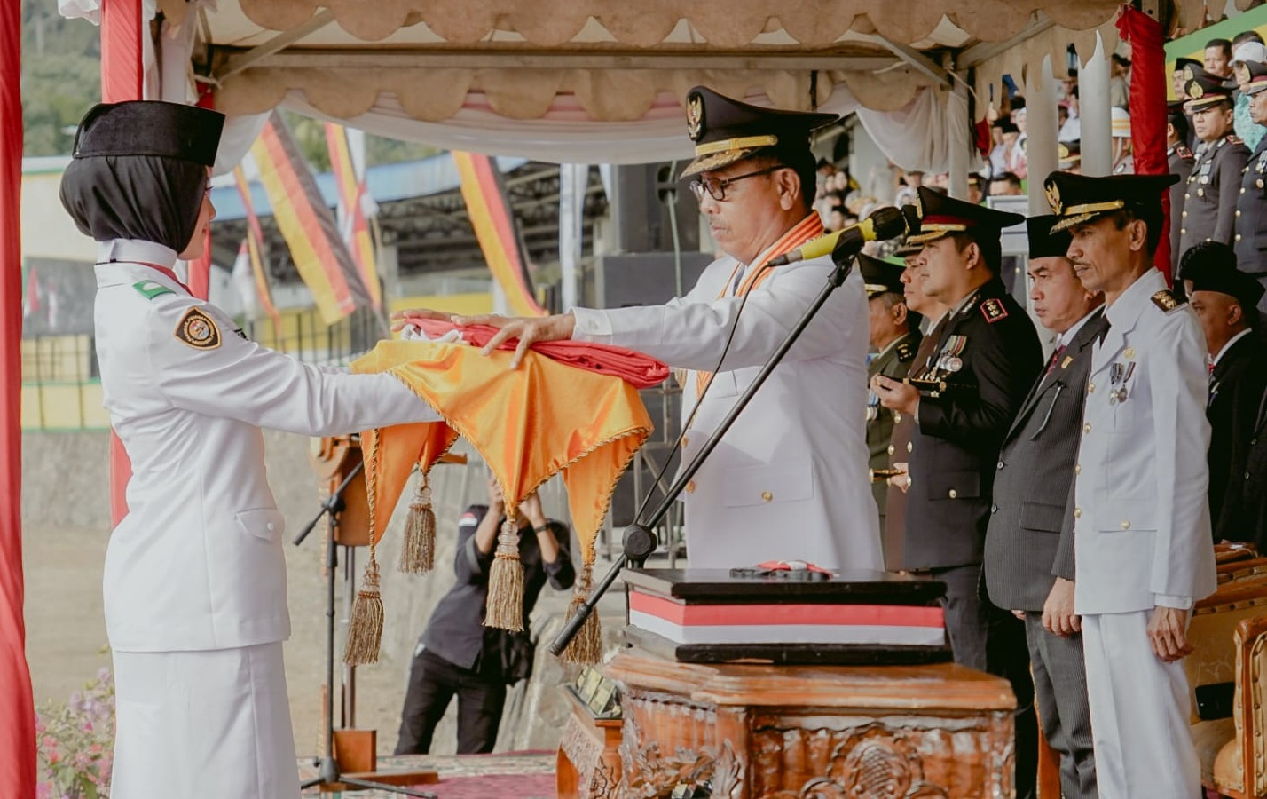 Bupati Solok Selatan Khairunas menyerahkan bendera Merah Putih kepada Paskibraka untuk dikibarkan pada Upacara Hari Kemerdekaan Republik Indonesia di GOR Rimbo Tangah, Senin (17/08/2026).