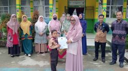 Kepala MIN 1 Solok Selatan, Amoi Liza, S.Pd.I menyerahkan hadiah kepada siswa MIN 1 Solok Selatan, Arkha Verdyon yang bberhasil meraih Juara 1 Kategori Laga Usia Dini Putra Kejuaraan Pencak Silat Open Championship Pangdam XX/TIB Cup.