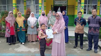 Kepala MIN 1 Solok Selatan, Amoi Liza, S.Pd.I menyerahkan hadiah kepada siswa MIN 1 Solok Selatan, Arkha Verdyon yang bberhasil meraih Juara 1 Kategori Laga Usia Dini Putra Kejuaraan Pencak Silat Open Championship Pangdam XX/TIB Cup.