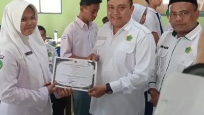 Kepala Kantor Kementrian Agama Kabupaten Solok Selatan Fitriyoni, SH., MH di dampingi Kasi Pendis Putra Alizar, SH.I., MH saat penyerahan piagam penghargaan kepada siswa peserta OMI Kabupaten.
