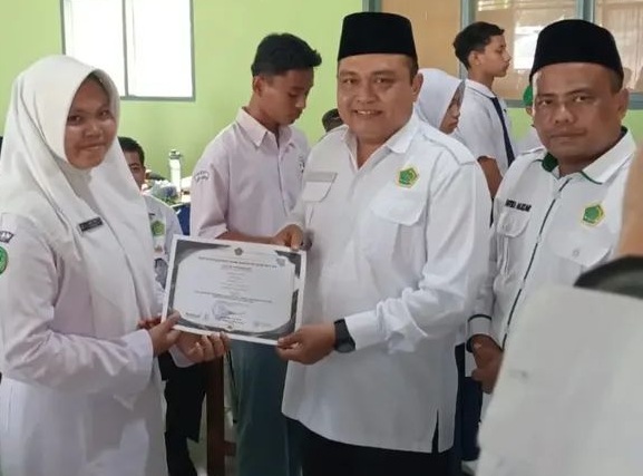 Kepala Kantor Kementrian Agama Kabupaten Solok Selatan Fitriyoni, SH., MH di dampingi Kasi Pendis Putra Alizar, SH.I., MH saat penyerahan piagam penghargaan kepada siswa peserta OMI Kabupaten.  