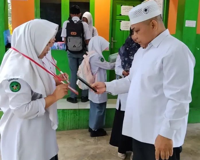 Kepala MAN 1 Solok Selatan H. Jasrul, S.Pd saat memeriksa scan barkot kehadiran siswa, Rabu (02/09/2026).