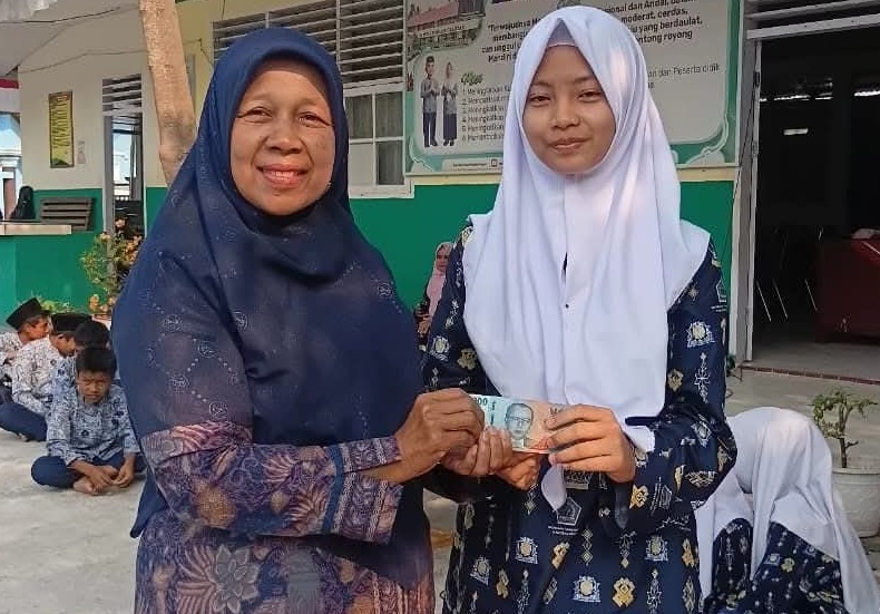 Kepala MTsN 6 Solok Selatan Lili Defita, S.Pd saat memberikan penghargaan kepada siswi berprestasi.