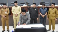 Ketua DPRD Kota Padang menandatangi dokumen yang dihasilkan melalui DPRD Kota Padang disaksikan Wali Kota dan para Wakil Ketua, Sekda dan Sekwan.