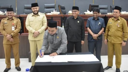 Ketua DPRD Kota Padang menandatangi dokumen yang dihasilkan melalui DPRD Kota Padang disaksikan Wali Kota dan para Wakil Ketua, Sekda dan Sekwan.