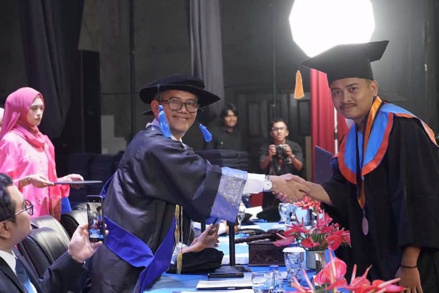 Rektor ISI Padangpanjang Dr. Febri Yulika, S.Ag., M.Hum saat menyalami salah satu lulusan saat Wisuda Program Sarjana Terapan, Sarjan dan Program Magister Periode I Tahun Akademik 2026/2027 di Gedung Pertunjukan Hoeridjah Adam, Selasa (15/09/20269). 