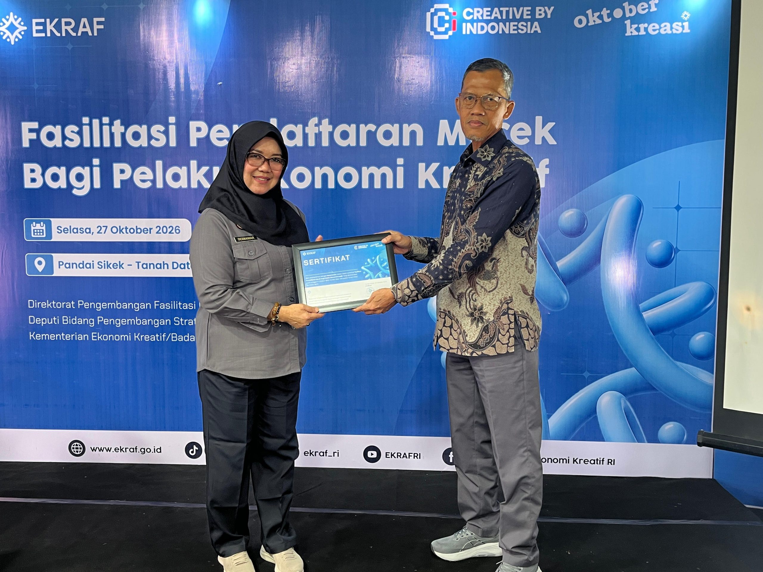 Tenaga Ahli Menteri Bidang Efektivitas dan Anggaran Milik Negara Kemenkraf Muhammad Idris, saat menyerahkan cinderamata kepada Desmaniar, SH., M.Si dari Kanwil Kementrian Hukum Sumbar sebagai narusumber Fasilitasi Pendaftaran Merek Bagi Pelaku Ekonomi Kreatif di Kantor Wali Nagari Pandai Sikek, Selasa (27/10/2026).